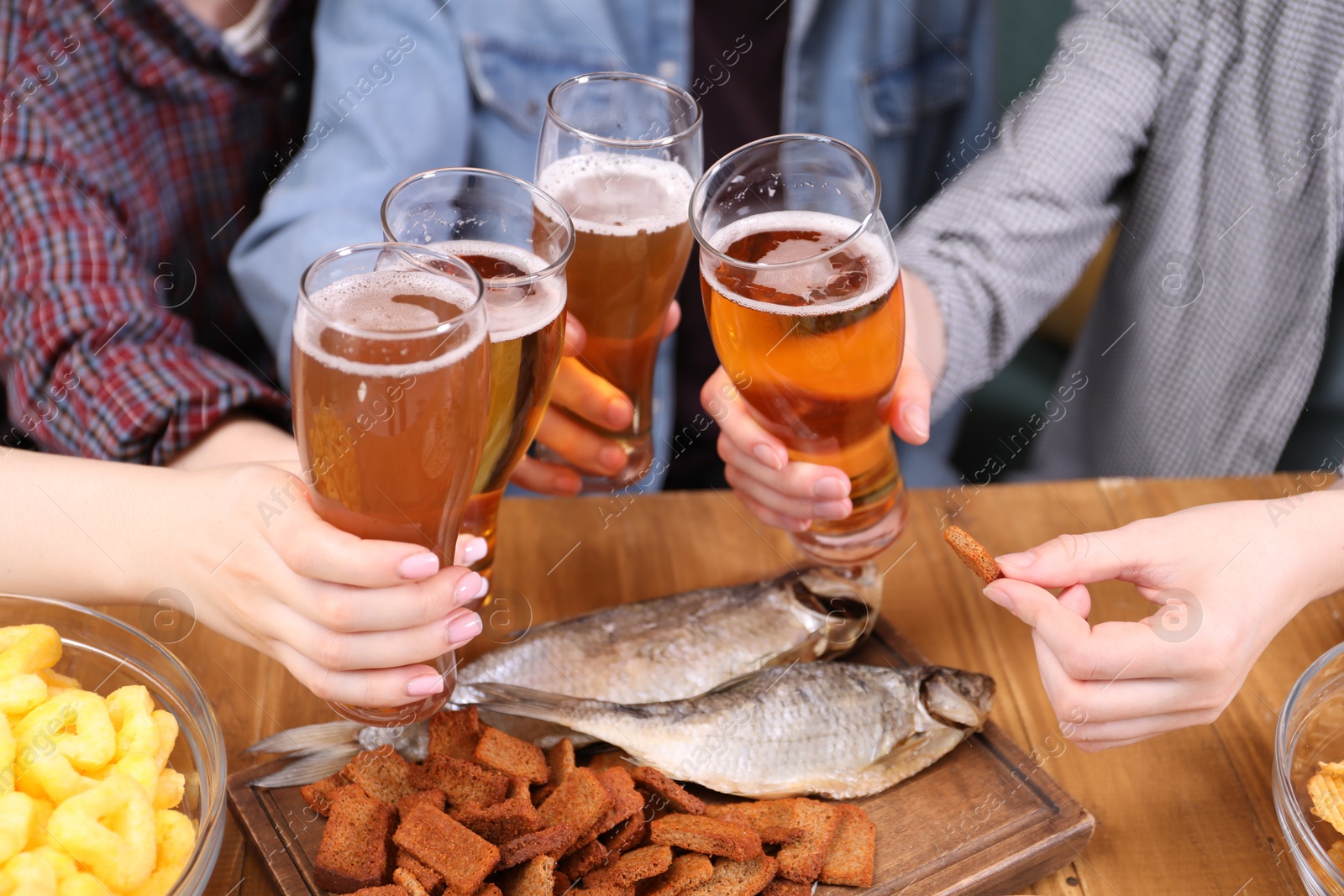 Friends with beer and snacks at wooden table, closeup Photo of Friends with beer and snacks at wooden table, closeup