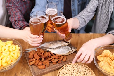 Photo of Friends with beer and snacks at wooden table, closeup