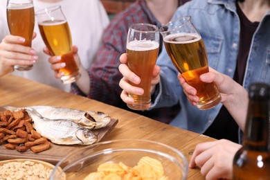 Photo of Friends with beer and snacks at wooden table, closeup