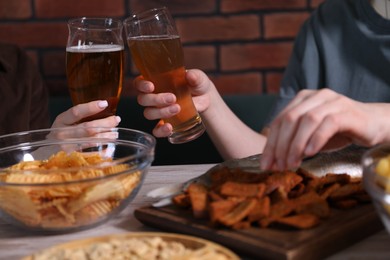 Photo of Friends with beer and snacks at white wooden table, closeup