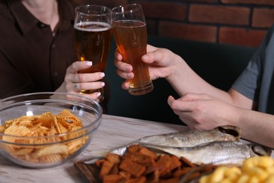 Photo of Friends with beer and snacks at white wooden table, closeup