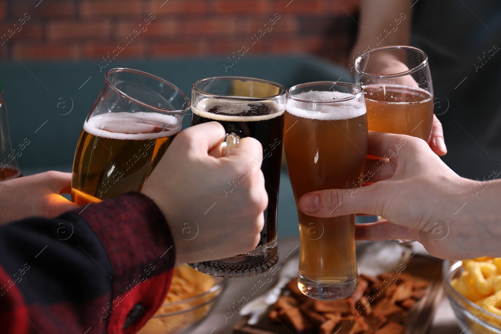 Friends clinking glasses of beer indoors, closeup Photo of Friends clinking glasses of beer indoors, closeup