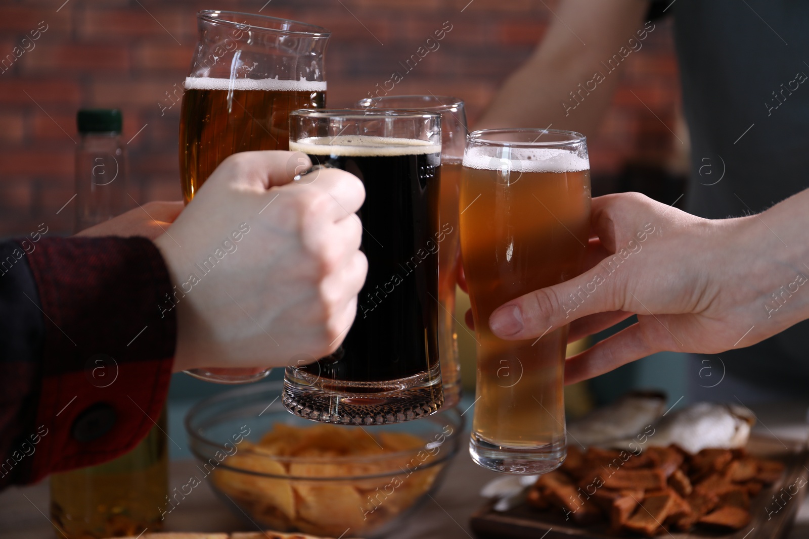 Friends clinking glasses of beer indoors, closeup Photo of Friends clinking glasses of beer indoors, closeup