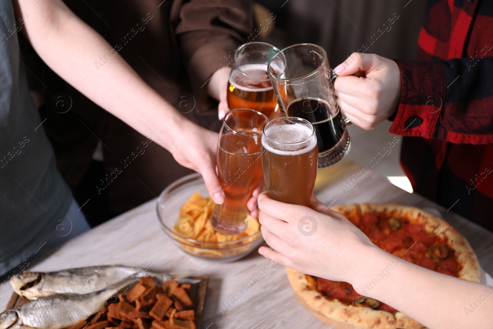 Friends clinking glasses of beer at white wooden table, closeup Photo of Friends clinking glasses of beer at white wooden table, closeup
