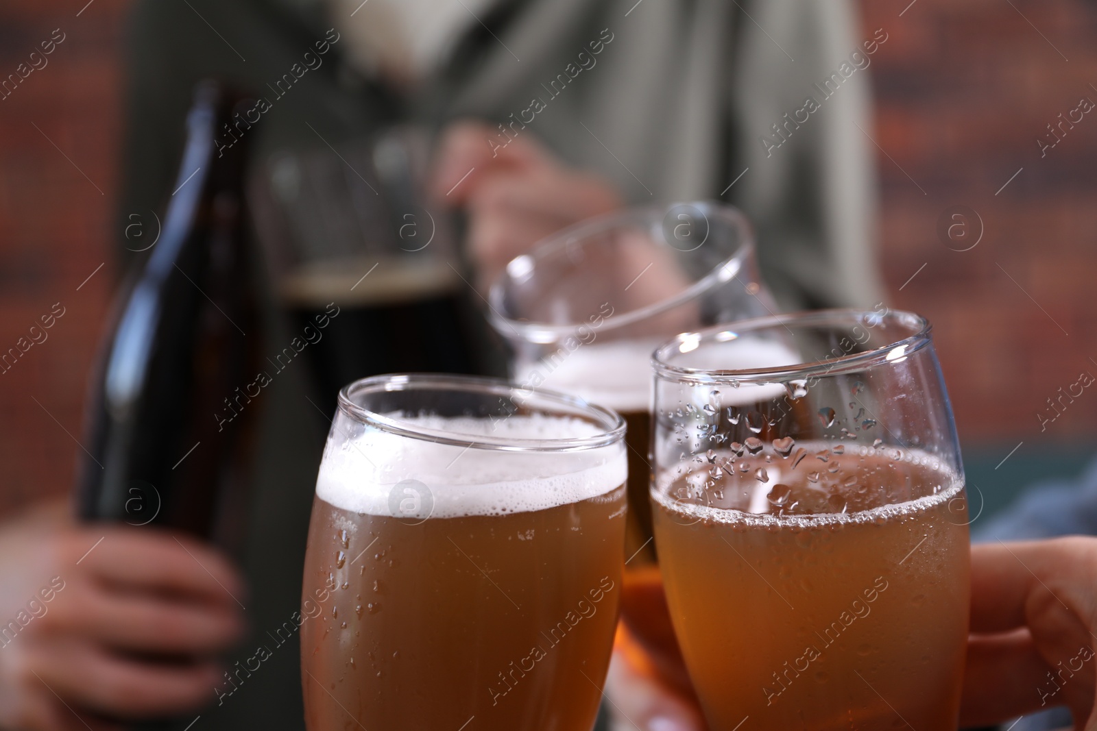 Friends clinking glasses of beer indoors, closeup Photo of Friends clinking glasses of beer indoors, closeup
