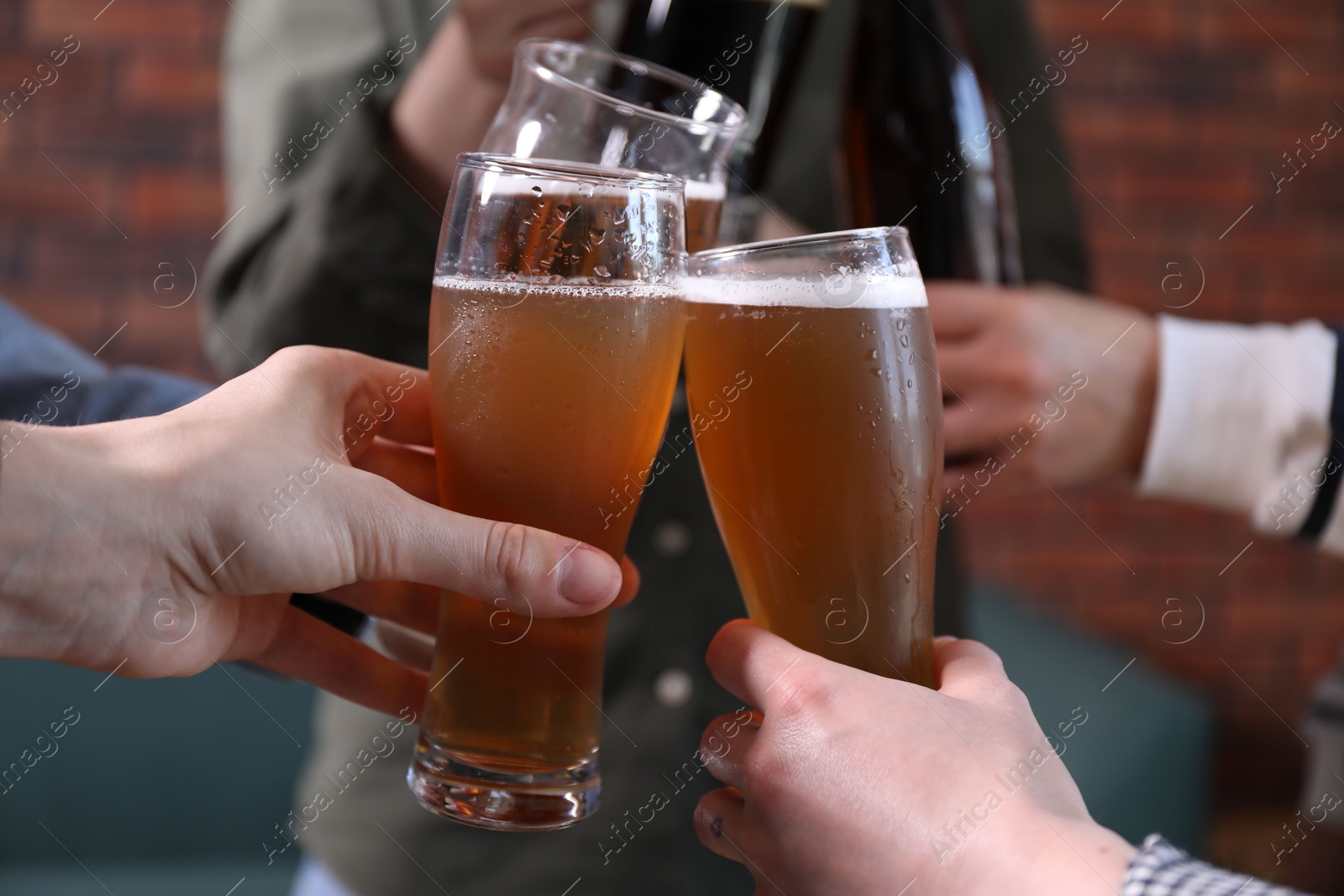 Friends clinking glasses of beer indoors, closeup Photo of Friends clinking glasses of beer indoors, closeup
