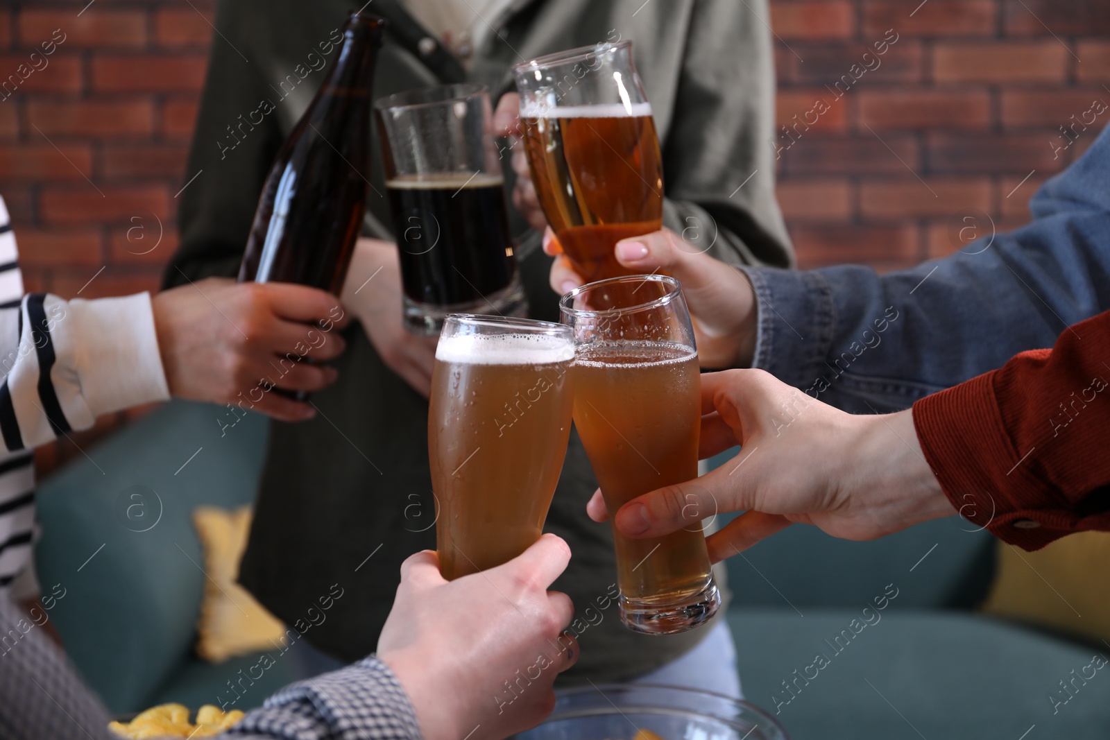 Friends clinking glasses of beer indoors, closeup Photo of Friends clinking glasses of beer indoors, closeup
