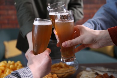 Photo of Friends clinking glasses of beer at table, closeup