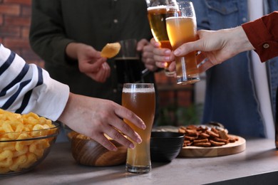 Photo of Friends with beer and snacks at grey table, closeup