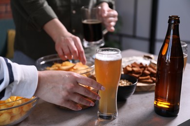 Photo of Friends with beer and snacks at grey table, closeup