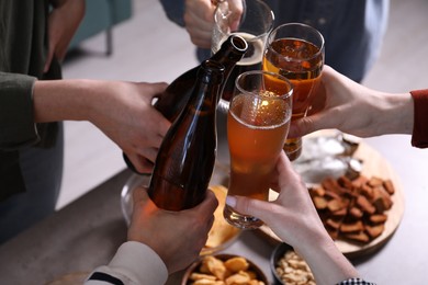 Photo of Friends clinking glasses of beer at table, closeup