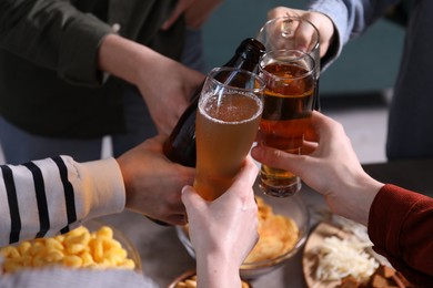 Photo of Friends clinking glasses of beer at table, closeup