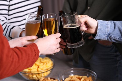 Photo of Friends clinking glasses of beer at table, closeup