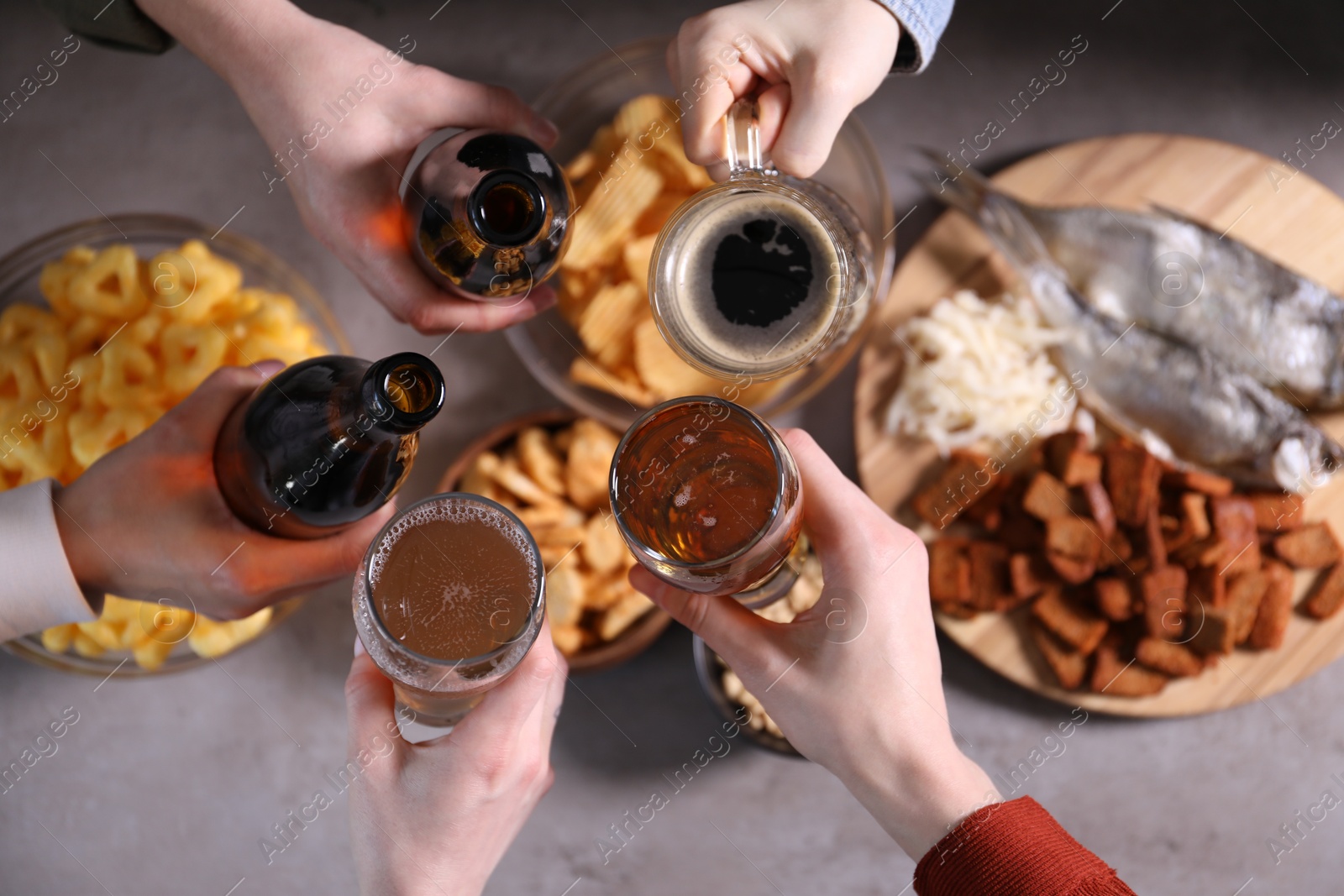 Friends clinking glasses of beer at grey table, top view Photo of Friends clinking glasses of beer at grey table, top view