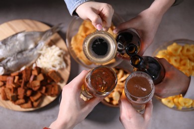 Photo of Friends clinking glasses of beer at grey table, top view