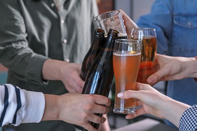 Photo of Friends clinking glasses of beer indoors, closeup