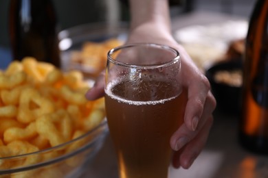 Photo of Woman with glass of beer and snacks at table indoors, closeup