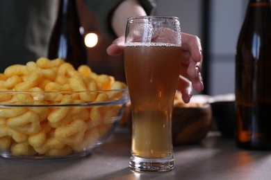 Photo of Woman with glass of beer and snacks at table indoors, closeup