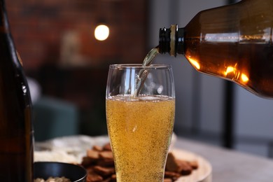 Photo of Pouring beer into glass at table, closeup