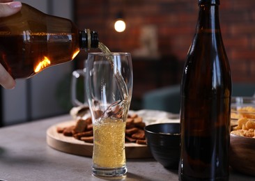 Photo of Woman pouring beer into glass at grey table, closeup