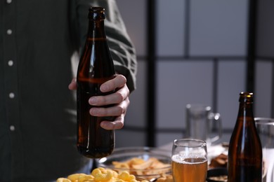 Photo of Woman with bottle of beer indoors, closeup