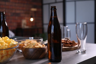Photo of Beer, glasses and snacks on grey table indoors, closeup