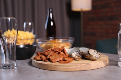 Photo of Beer, glasses and snacks on grey table indoors, closeup
