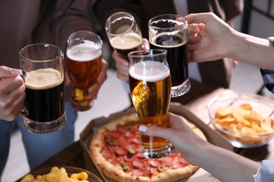 Photo of Friends clinking glasses of beer at table, closeup
