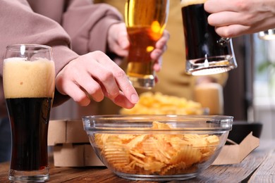 Photo of Friends with beer and snacks at wooden table, closeup