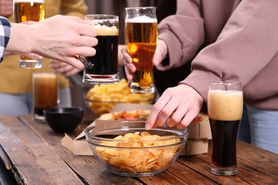 Photo of Friends with beer and snacks at wooden table, closeup