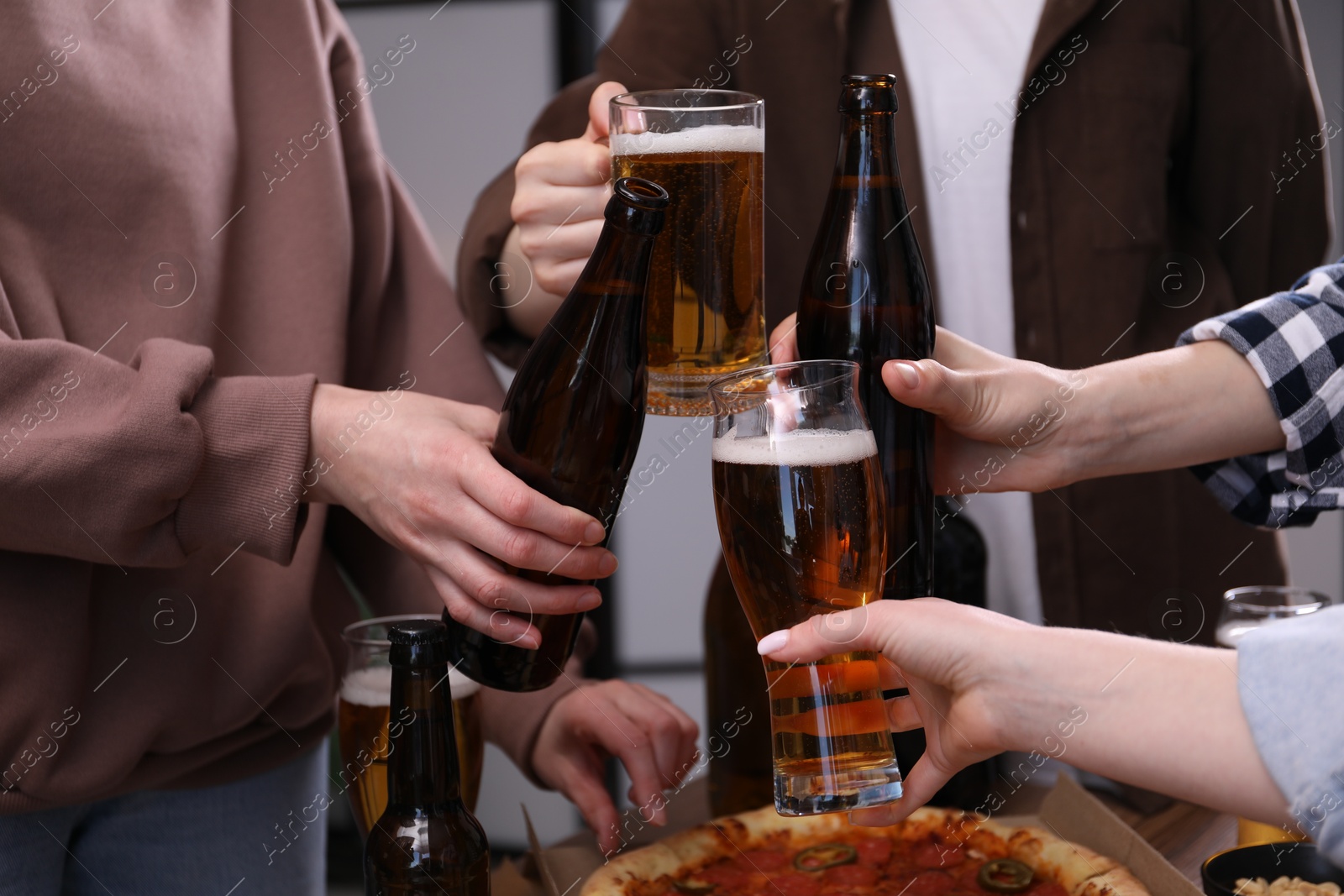 Friends clinking glasses of beer indoors, closeup Photo of Friends clinking glasses of beer indoors, closeup