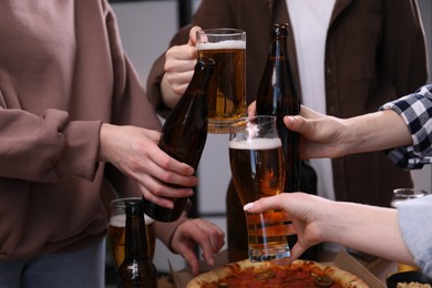 Photo of Friends clinking glasses of beer indoors, closeup