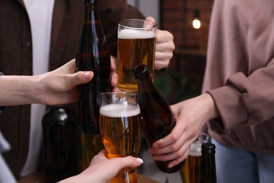 Photo of Friends clinking glasses of beer indoors, closeup