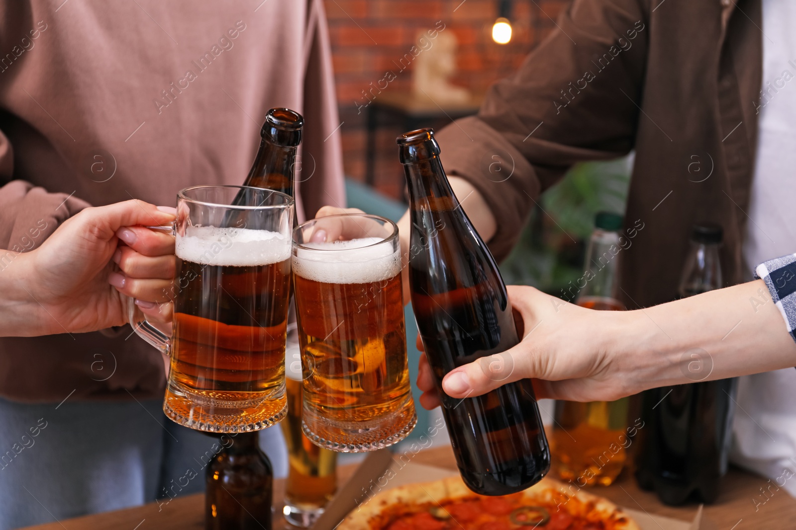 Friends clinking glasses of beer indoors, closeup Photo of Friends clinking glasses of beer indoors, closeup