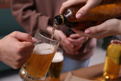 Photo of Woman pouring beer into her friend's glass indoors, closeup