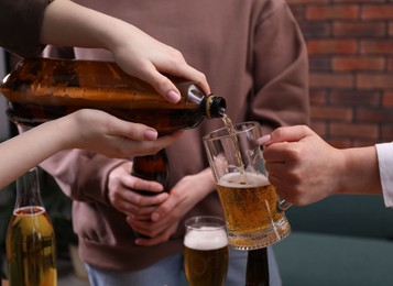 Photo of Woman pouring beer into her friend's glass indoors, closeup