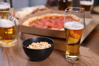 Photo of Beer and snacks on wooden table indoors, closeup