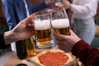 Photo of Friends clinking glasses of beer at table, closeup