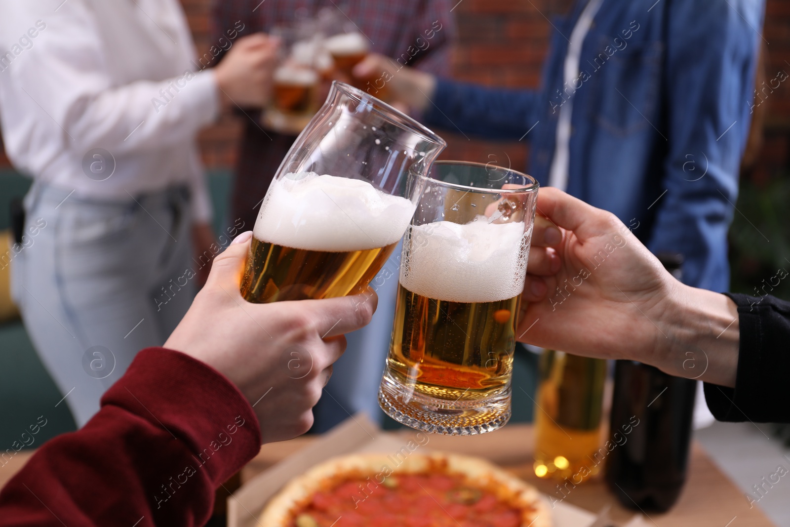 Friends clinking glasses of beer at table, closeup Photo of Friends clinking glasses of beer at table, closeup