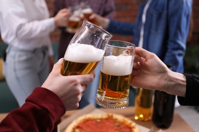 Photo of Friends clinking glasses of beer at table, closeup