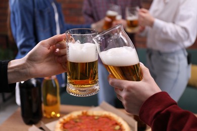 Photo of Friends clinking glasses of beer at table, closeup