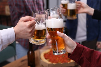 Photo of Friends clinking glasses of beer at table, closeup