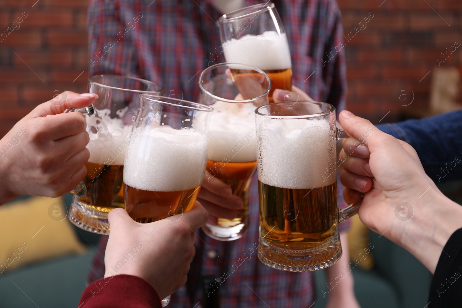 Friends clinking glasses of beer indoors, closeup Photo of Friends clinking glasses of beer indoors, closeup