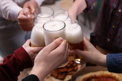 Photo of Friends clinking glasses of beer at table, closeup