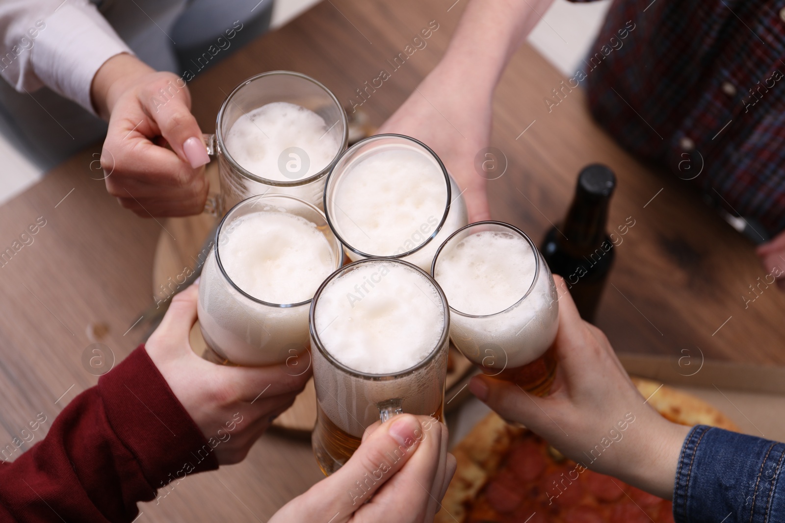 Friends clinking glasses of beer at wooden table, closeup Photo of Friends clinking glasses of beer at wooden table, closeup