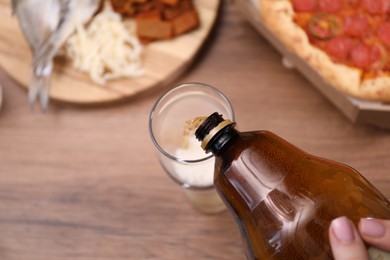 Photo of Woman pouring beer into glass at wooden table, above view