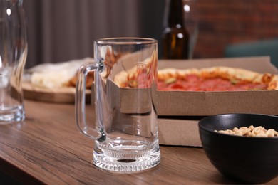 Photo of Empty beer glasses and snacks on wooden table indoors, closeup