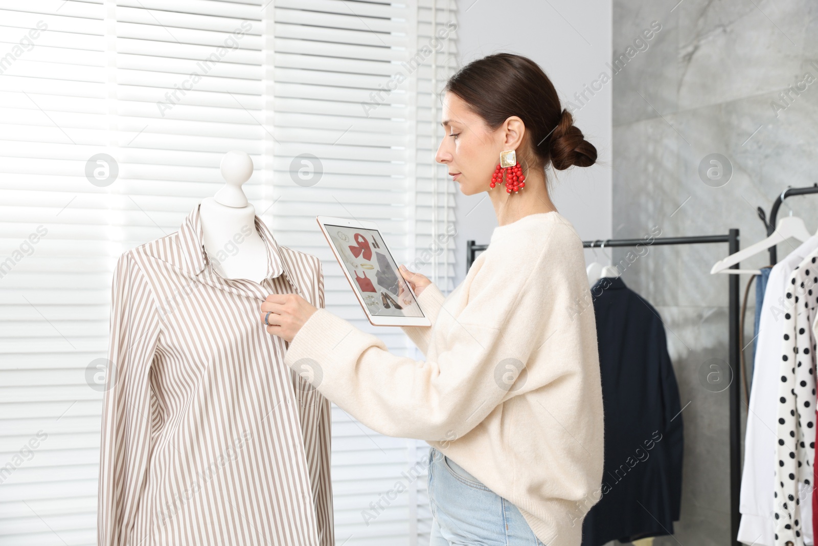 Professional stylist with picture of outfit on tablet working indoors Photo of Professional stylist with picture of outfit on tablet working indoors
