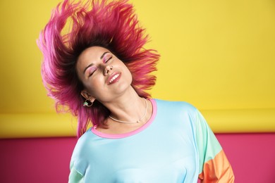 Photo of Beautiful woman with pink dyed hair shaking head on color background