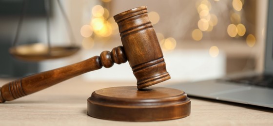 Photo of Judge's gavel on wooden table in office, closeup. Bokeh effect